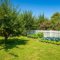 A lush, verdant garden, brimming with a bountiful array of fruit trees laden with ripe fruit, vibrant vegetable patches, and a profusion of colorful flowering plants, is beautifully framed by a pristine white picket fence beneath a clear, sunny blue sky